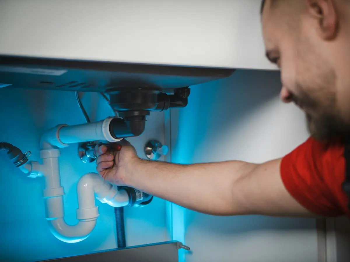 Sfeerbeeld: installateur sluit een sifon aan onder een lavabo