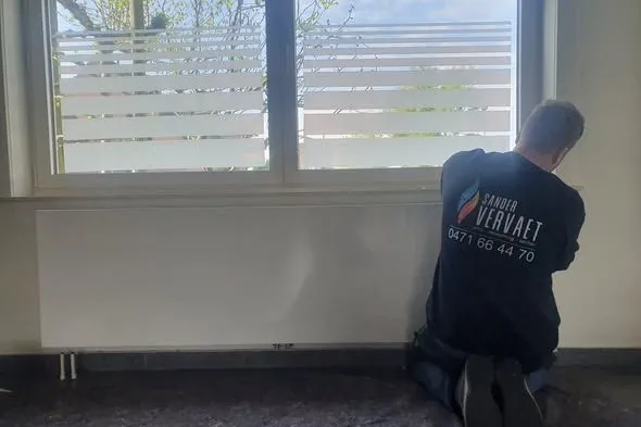Sander Vervaet monteert een radiator onder het raam